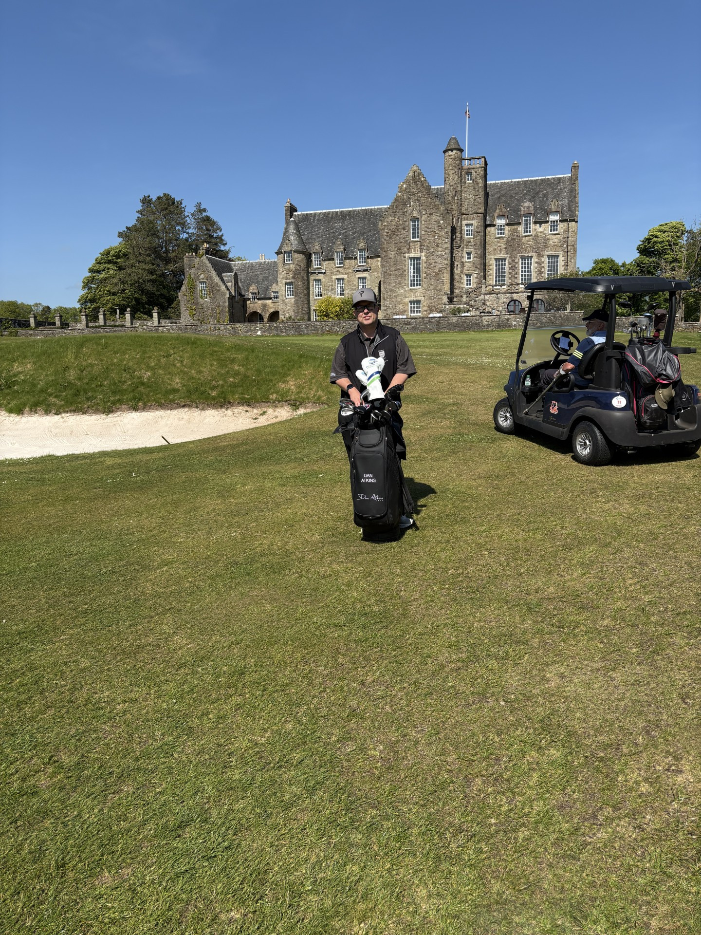A Picture of Dan on a golf course with his golf bag in front of Him